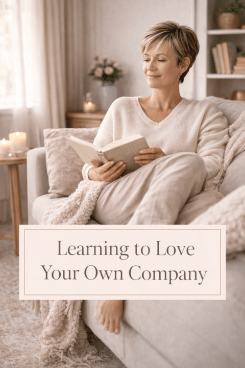 Midlife woman with highlighted pixie hair reading alone on a sofa, enjoying peaceful solitude in a softly lit living room.