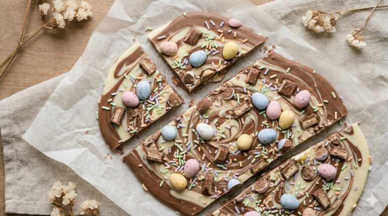 Easter chocolate bark made with swirled milk and white chocolate and topped with pastel mini eggs and sprinkles on parchment paper.