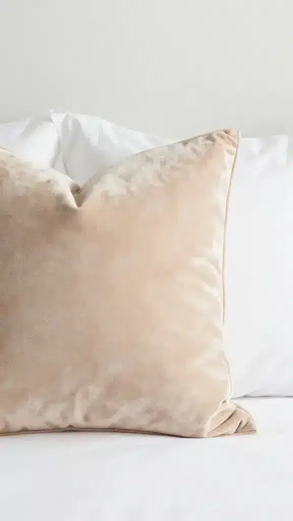 closeup champagne velvet decorative pillow on white bedding